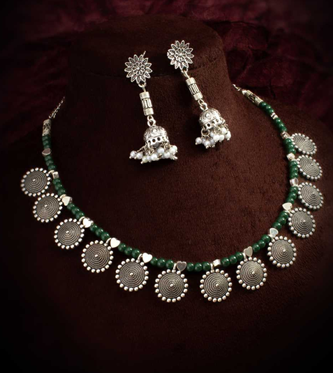 Necklace and earrings set on a black mannequin bust with a plain background